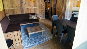 A rustic wooden interior with a sofa, a dining table, and chairs. - Camping 2000 - Sahara tent XXL (Osecná)