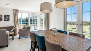 Un espace de salle à manger moderne avec une table en bois, des chaises et des luminaires suspendus.