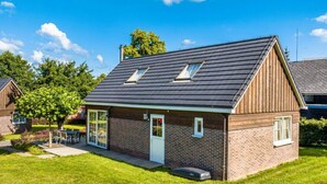 Une maison de plain-pied avec un toit en pente, une porte d’entrée et un petit porche.