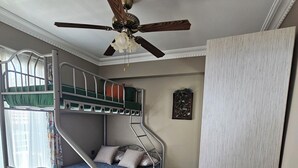 A bunk bed room with a ceiling fan, a small table with a lantern, and a patterned floor. - ARİFE REZİDANCE NO.2 (Didim)