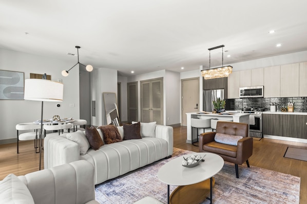 A modern living room with a white sofa, a coffee table, and a dining area with a white table and chairs.
