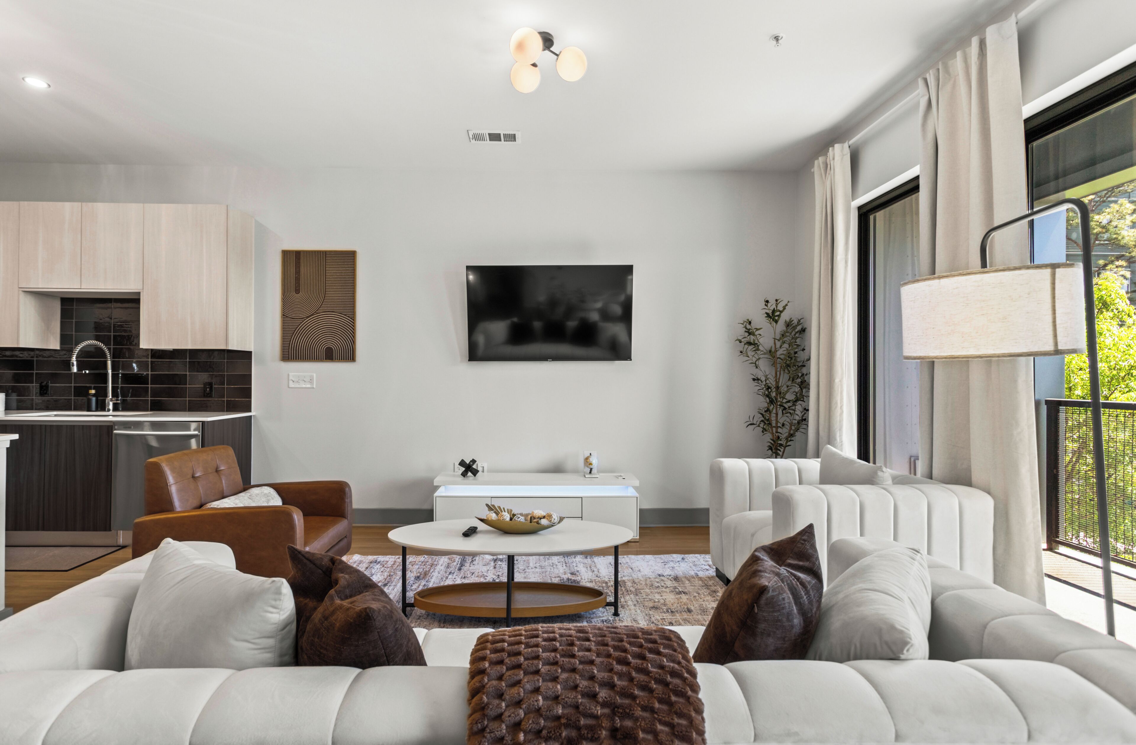 A modern living room with a sofa, coffee table, and a dining area with a TV.