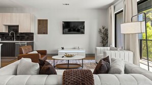 A modern living room with a sofa, coffee table, and a dining area with a TV. - Lux Mocha Downtown Self Check-in Balcony (Atlanta)