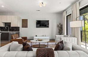 A modern living room with a sofa, coffee table, and a dining area with a TV. - Lux Mocha Downtown Self Check-in Balcony (Atlanta)