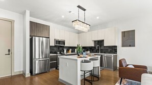 A modern kitchen with stainless steel appliances, a central island with bar stools, and a hanging light fixture. - Lux Mocha Downtown Self Check-in Balcony (Atlanta)