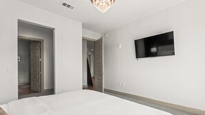 A hotel room with a large bed, a flat-screen TV mounted on the wall, and a door leading to another room. - Lux Mocha Downtown Self Check-in Balcony (Atlanta)