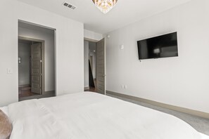 A hotel room with a large bed, a flat-screen TV mounted on the wall, and a door leading to another room. - Lux Mocha Downtown Self Check-in Balcony (Atlanta)