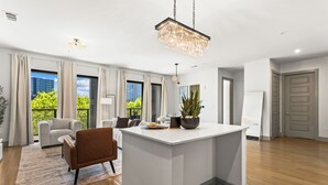A modern living room with a central island, a dining area, and a view of a cityscape through large windows. - Lux Mocha Downtown Self Check-in Balcony (Atlanta)