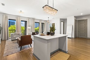 A modern living room with a central island, a dining area, and a view of a cityscape through large windows. - Lux Mocha Downtown Self Check-in Balcony (Atlanta)