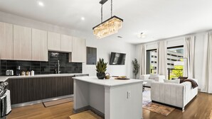 A modern kitchen with a central island, a dining area with a sofa, and a living room with a large window. - Lux Mocha Downtown Self Check-in Balcony (Atlanta)