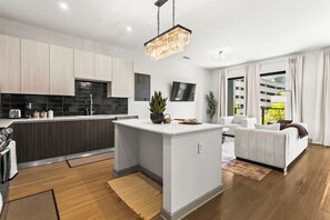 A modern kitchen with a central island, a dining area with a sofa, and a living room with a large window.