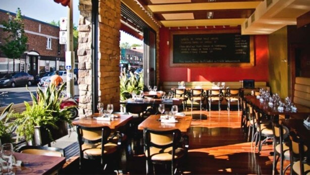 An outdoor dining area with stone pillars, wooden tables, and chairs. - ROSEMONT: Nice apartment 2 steps from Molson Park! (Montréal)