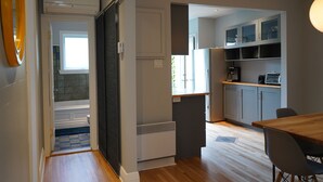 A modern kitchen with grey cabinets, a wooden dining table, and a built-in microwave. - ROSEMONT: Nice apartment 2 steps from Molson Park! (Montréal)