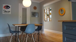 A dining area with a wooden table and blue chairs, a hanging light fixture, and a clock on the wall. - ROSEMONT: Nice apartment 2 steps from Molson Park! (Montréal)