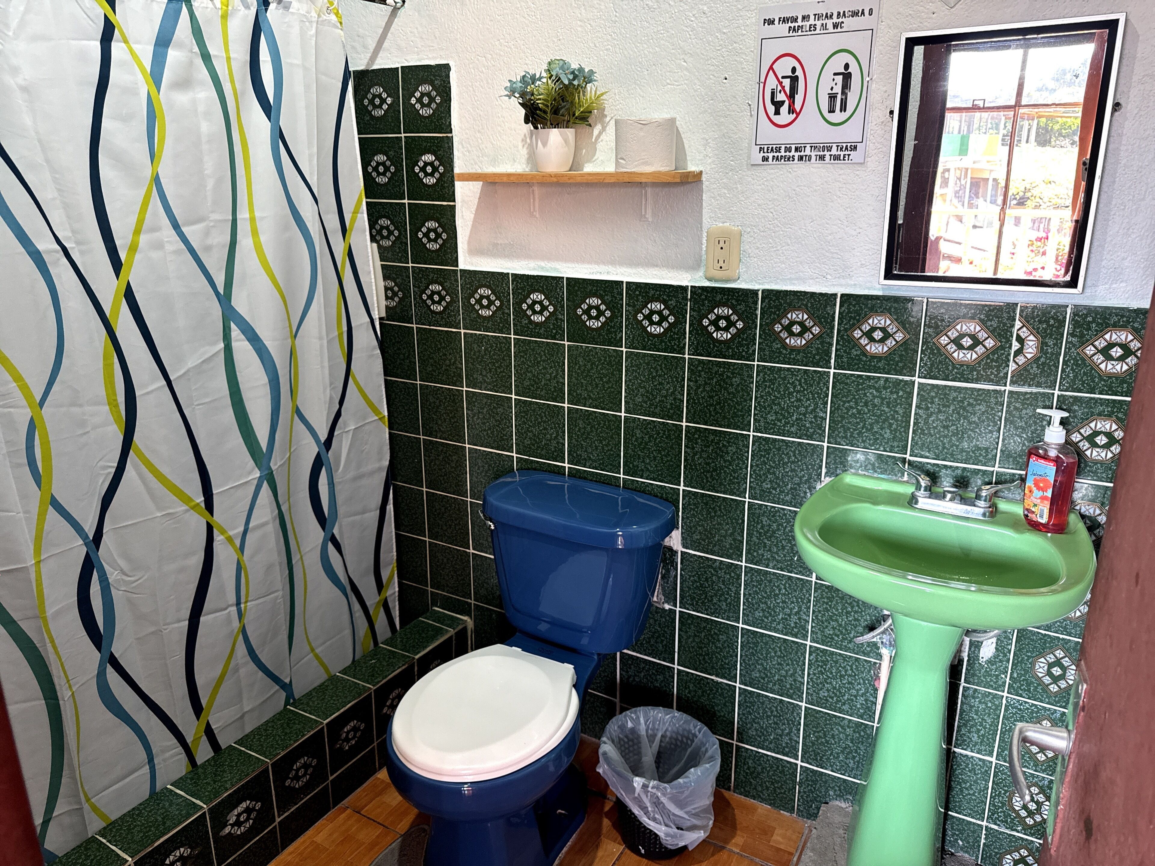A bathroom with a blue toilet, green sink, and patterned tiles.