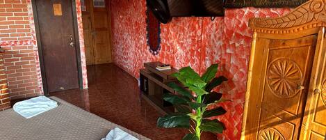 A hotel room with two beds, a TV, a wooden cabinet, and a potted plant.