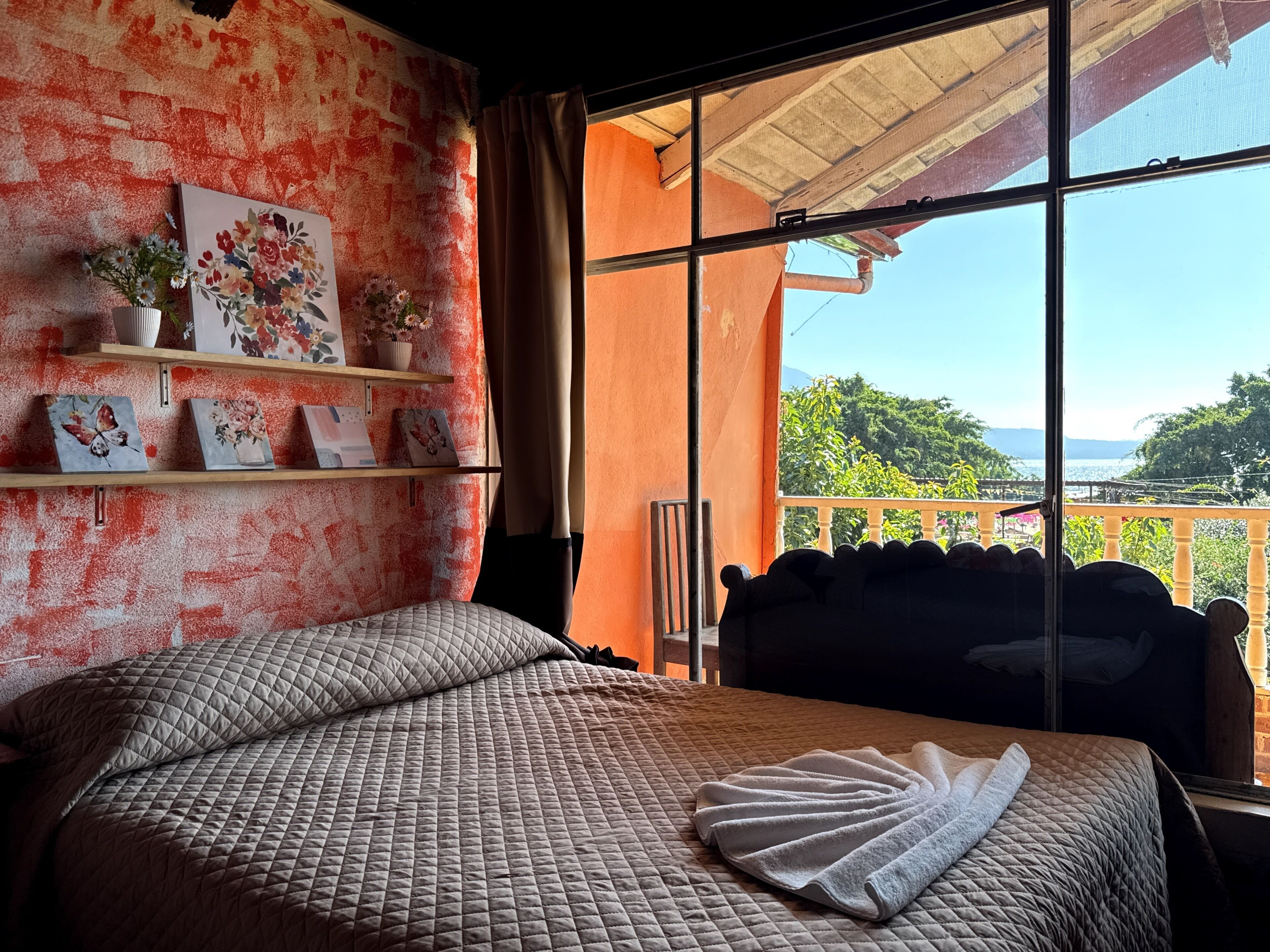 Ein Schlafzimmer mit einem Bett, einem Fenster mit Blick und einem Regal mit Dekoration.