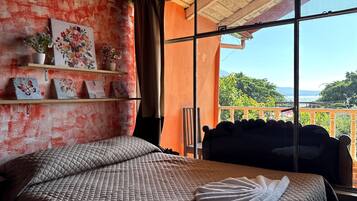 Ein Schlafzimmer mit einem Bett, einem Fenster mit Blick und einem Regal mit Dekoration.