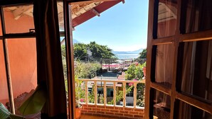 Una puerta de madera abierta que da a un balcón con vistas a un paisaje montañoso y una masa de agua.
