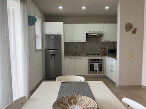A compact kitchen with white cabinets, a stainless steel refrigerator, a microwave, and a gas stove. - Tracadero Marina 40 Apt, 1 Bdr. Sea View (Dominicus)