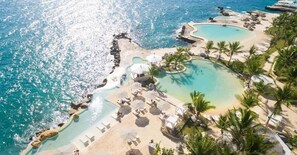 A resort with multiple swimming pools, a beach area, and lounge chairs. - Tracadero Marina 40 Apt, 1 Bdr. Sea View (Dominicus)