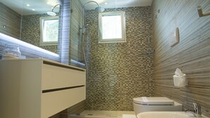 A modern bathroom with a large mirror, a shower, a toilet, and a sink.