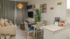 Uma sala de estar moderna com sofá, mesa de jantar, cadeiras, máquina de café e um pequeno vaso de planta.