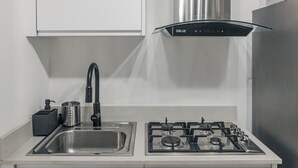 Uma cozinha moderna com uma pia de aço inoxidável, fogão a gás e exaustor preto.
