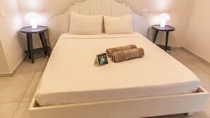 Un lit bien fait, avec des oreillers, une serviette pliée et une carte posée sur le lit. Il y a deux tables de chevet, chacune avec une lampe, de chaque côté du lit.