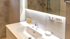 Une salle de bain moderne avec un grand lavabo blanc, un miroir et une cabine de douche en verre.