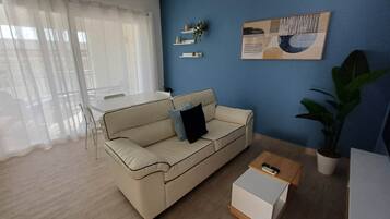 A living room with a beige sofa, a coffee table, a blue wall, and a painting.
