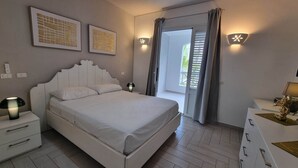 A bedroom with a bed, bedside tables, a dresser, wall art, and a balcony door. - Tracadero Marina 49 Apt, 1 Hab. (Dominicus)