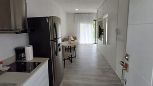 A modern kitchen with a built-in stove, a black refrigerator, and a dining area with a table and chairs.