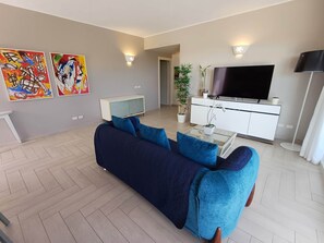A modern living room with a dark blue sofa, a flat-screen TV, and two abstract paintings on the wall.