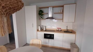 Eine kleine Küche mit weißen Schränken, einer Holz Arbeitsplatte, einem eingebauten Backofen und einer Pendelleuchte.