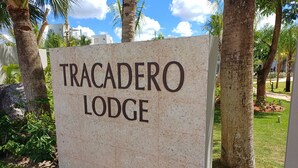 A sign for Tracadero Lodge with a clear view of the surrounding greenery and palm trees.