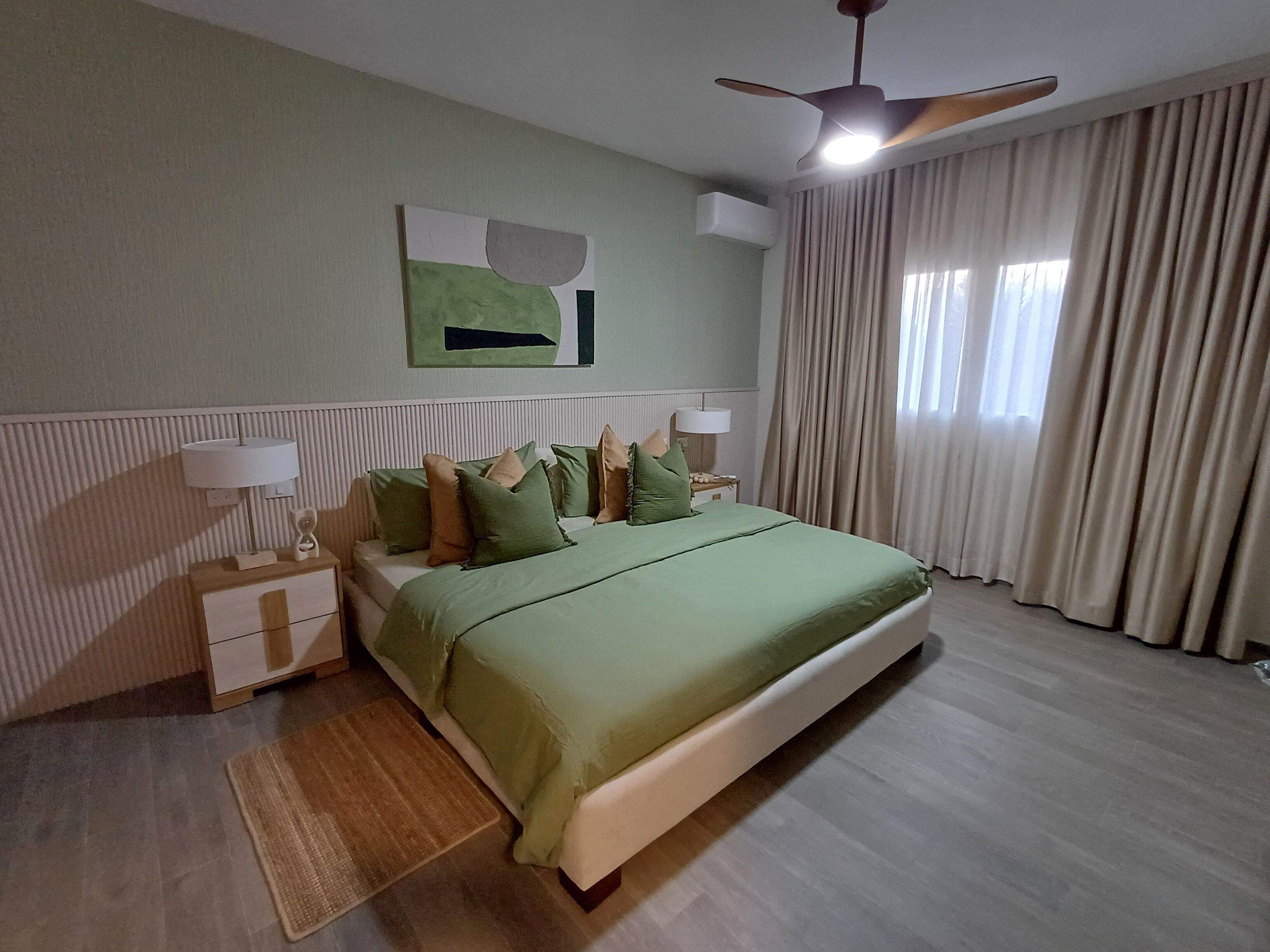 A bedroom with a bed, nightstands, a ceiling fan, and a window with curtains.