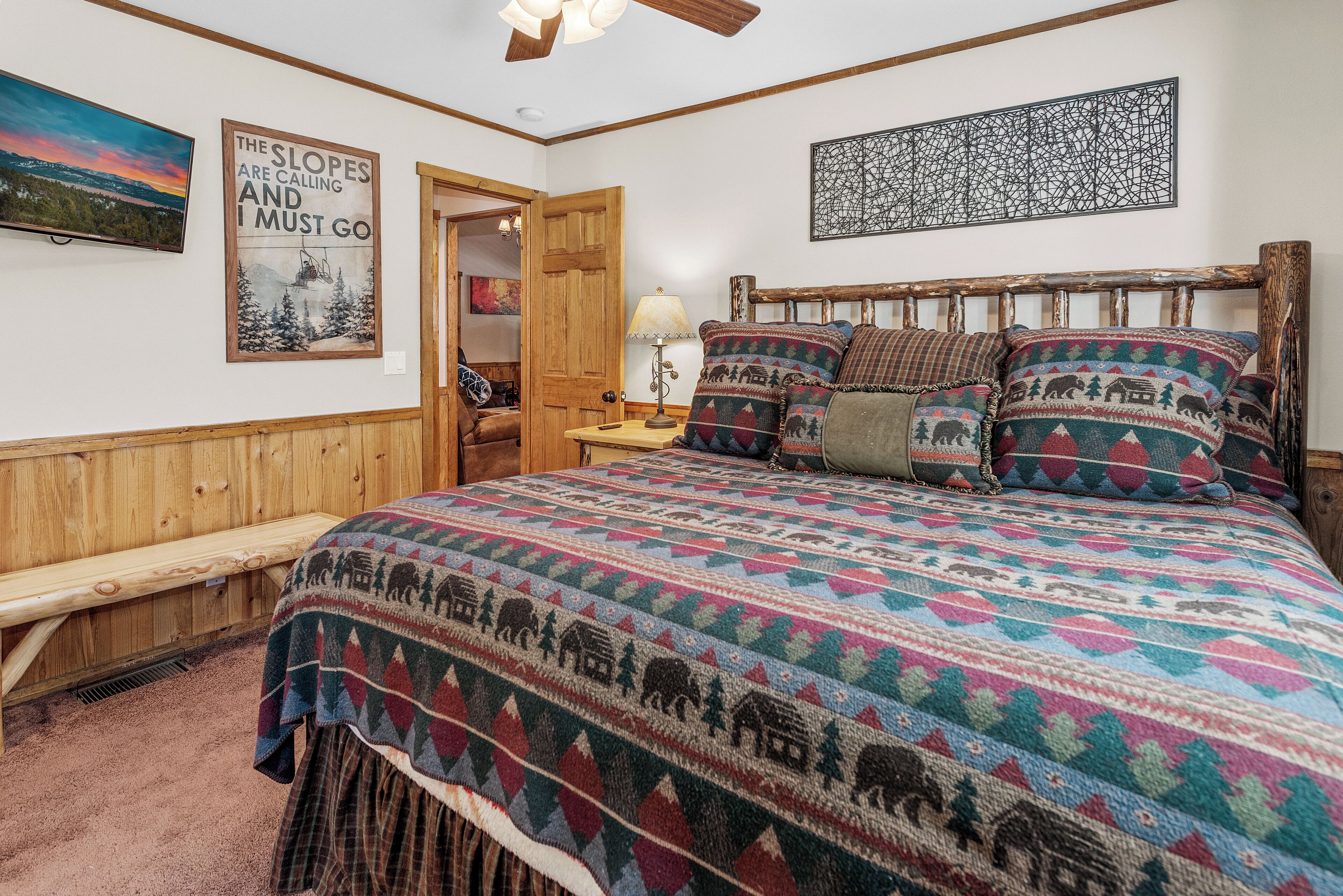 Une chambre à coucher accueillante, avec une tête de lit en bois, une courtepointe aux couleurs vives et un banc.