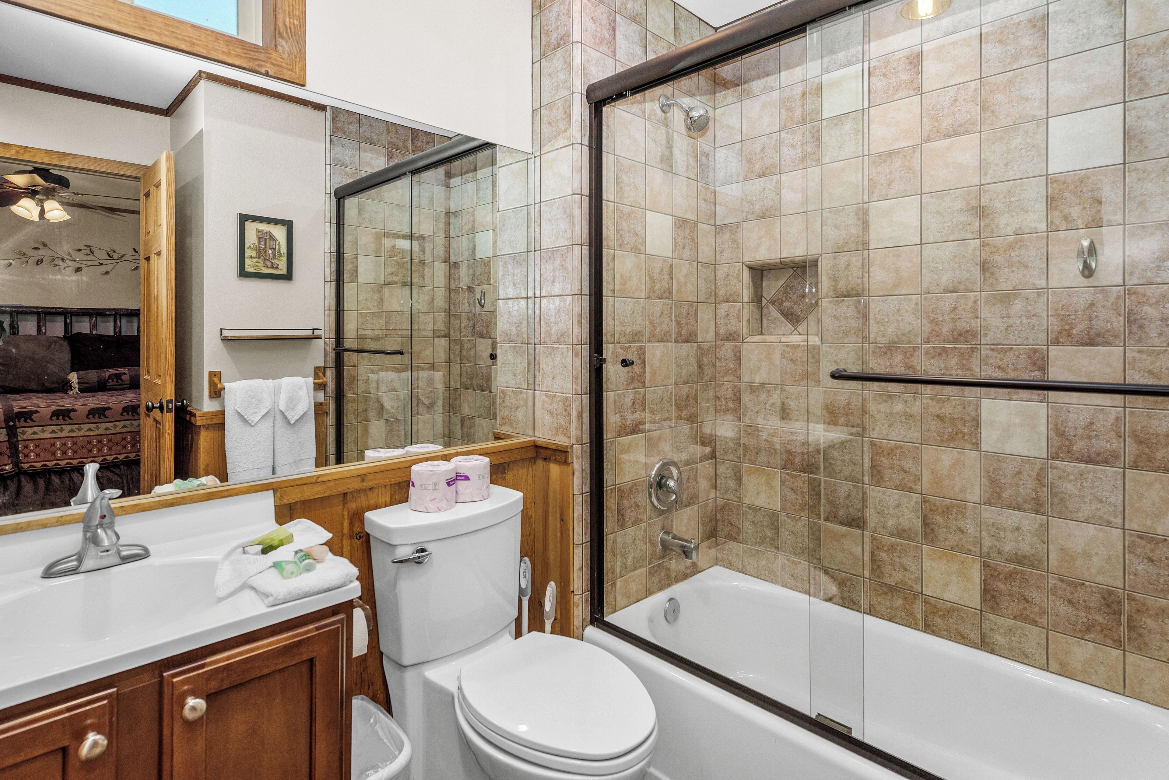Een badkamer met douche, toilet, wastafel en een grote spiegel.