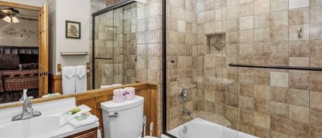 Een badkamer met douche, toilet, wastafel en een grote spiegel.