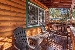 A wooden cabin with a porch featuring Adirondack chairs and a wooden table. - Blue Jay Chalet (Big Bear Lake)