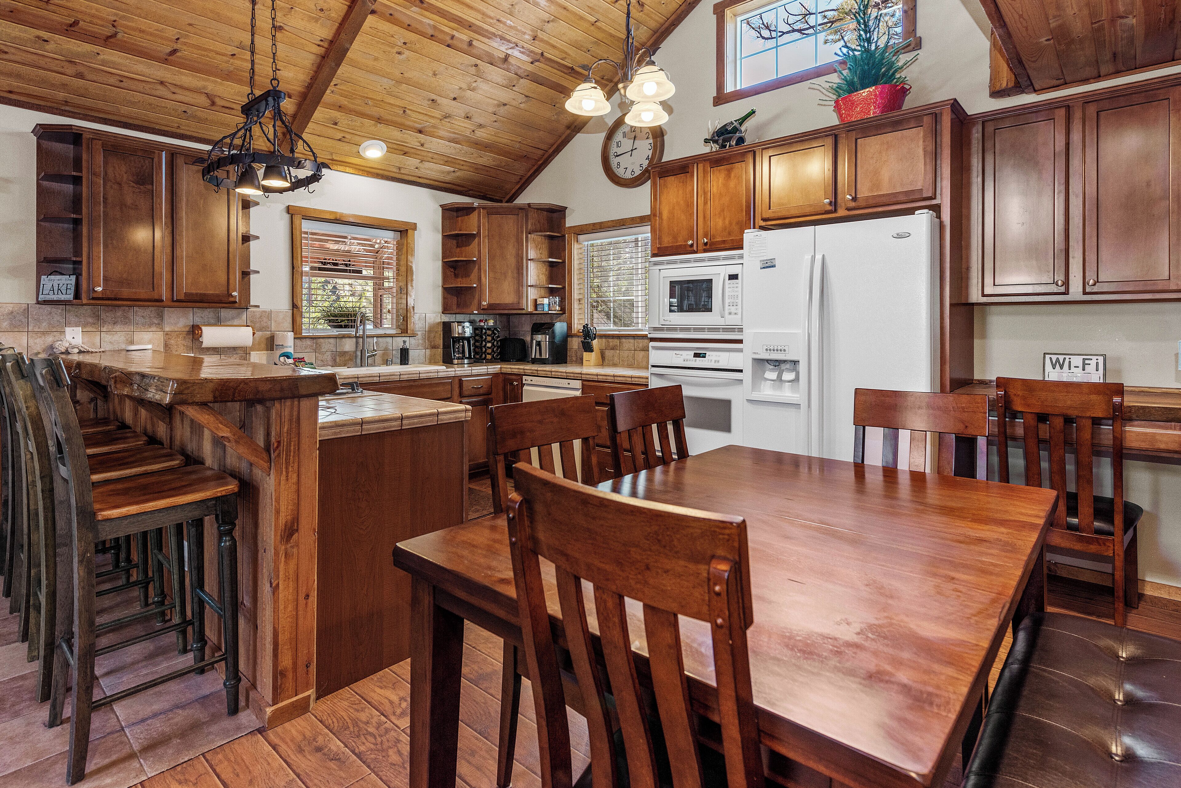 Una cocina amplia con armarios de madera, una isla central y un comedor con sillas de madera.