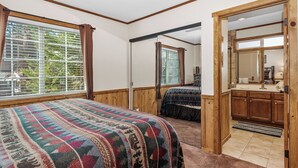 Une chambre avec un grand lit, une porte en bois et une fenêtre avec des rideaux.