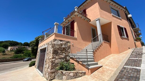Un bâtiment à deux étages, doté de fondations en pierre, d’un escalier menant à l’étage supérieur et d’un balcon agrémenté d’une balustrade.