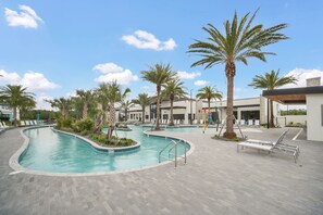 A swimming pool with a curved design, surrounded by palm trees and lounge chairs.