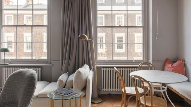 Une pièce confortable avec une grande fenêtre, un canapé, une table et une chaise.