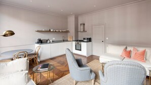 Un espace de vie compact comprenant un coin cuisine, un coin salon et un canapé avec des coussins.