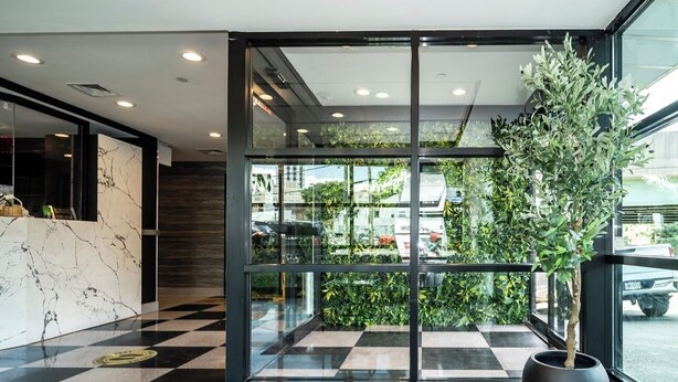 Un lobby moderno con piso a cuadros, una recepción con encimera de mármol y una planta grande en maceta.