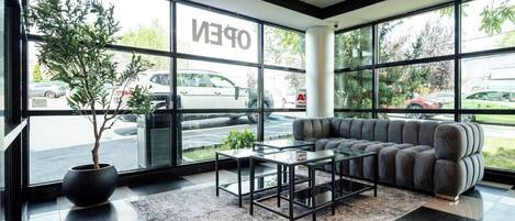 A modern interior with large windows, a sofa, a coffee table, and a potted plant.