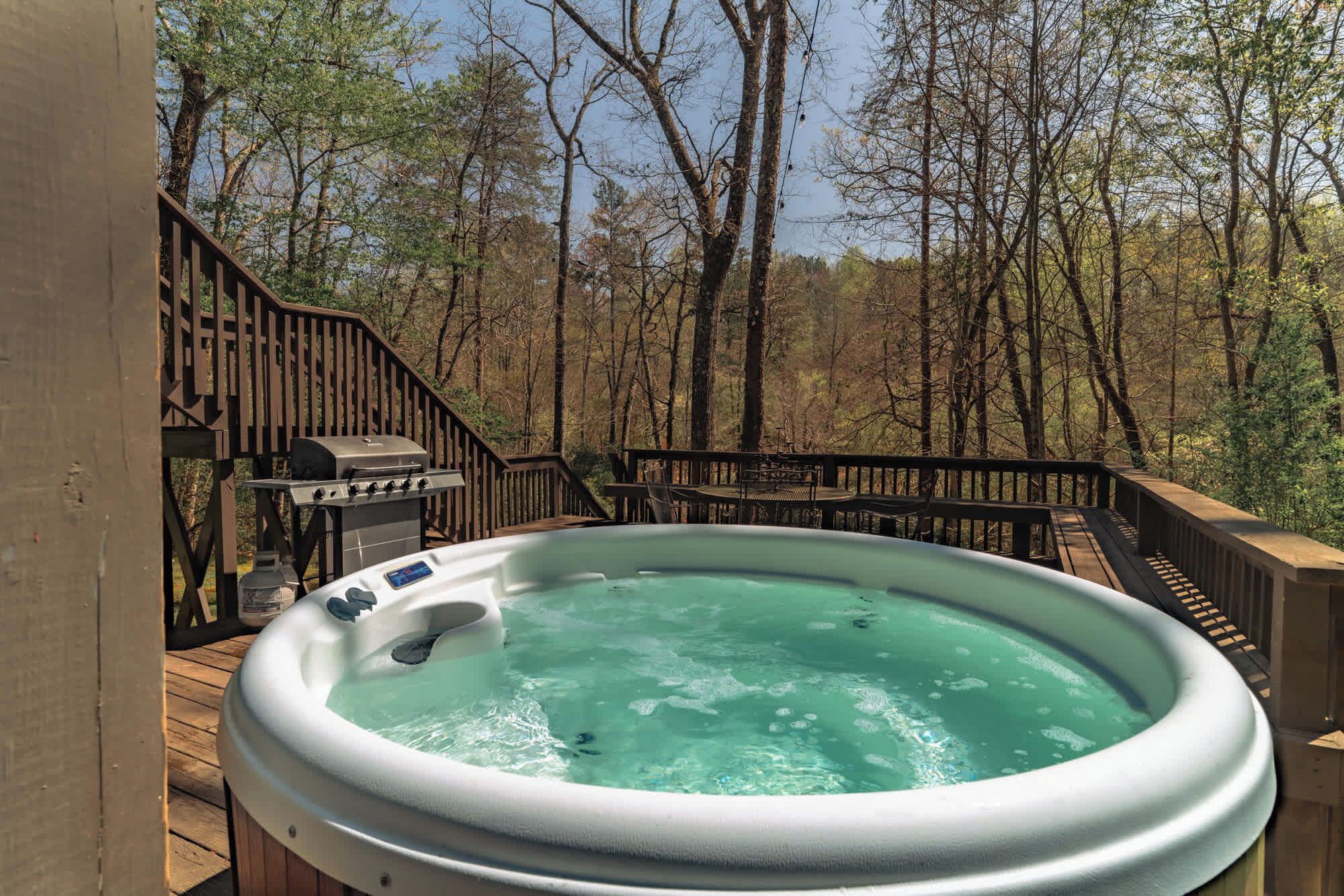 A hot tub on a wooden deck with a view of a forest.